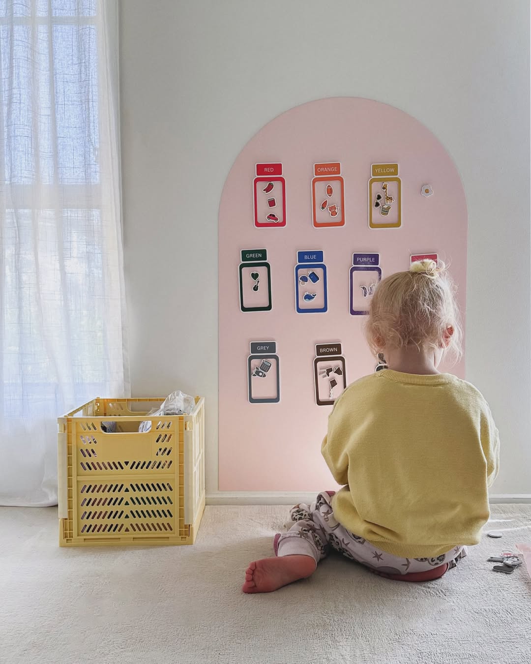 A child playing at a rose Magnetic Playwall set up as a screen-free play space at home